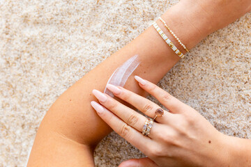 Woman applying lotion on skin at the beach