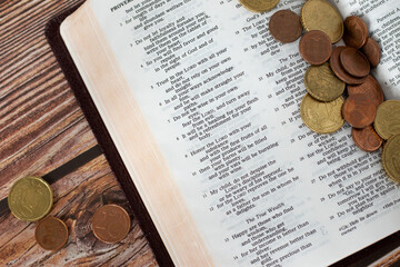 Coin money on open Holy Bible. Concept of Christian tithing, religious offering, and contribution...