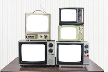 Five vintage televisions on old wood table with wall paper background and empty cut out screens. 