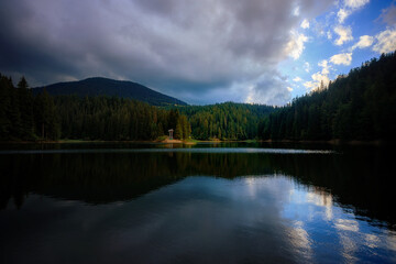 Fototapeta na wymiar Mountain lake among mountains with reflection, sky, clouds