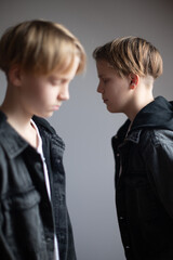 Two happy boys, happy brothers who are seriosly happily together. Brothers stay on grey background. modern tenagers.book cover. one boy in focus other out of focus