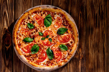 Delicious fragrant pizza with mozzarella, tomatoes and basil with tomato sauce on woden background. Top view