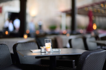 Empty outdoor european cafe at dusk. Stylish table decoration with borning candle. Vacant table.