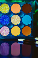 A palette of various colorful bright eyeshadows. Women's decorative cosmetics details and backgrounds. Makeup products. Professional makeup set. Female beauty concept. Blue yellow green orange colors.