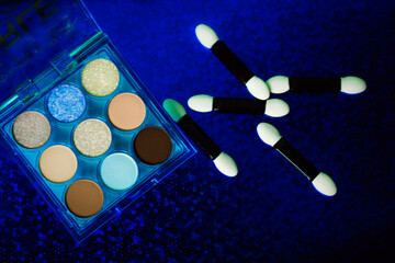 A palette of various colorful bright blue brown golden eyeshadows. Women's decorative cosmetics on dark blue background. Makeup product for makeup artist. Professional make-up set flatly Female beauty