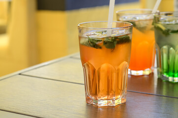 Glasses with fresh lemonade on the table. Orange lemonade with ice and mint