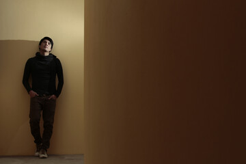 Hombre joven latino apoyado en la pared mirando arriban y pensando, concepto de tristeza y...