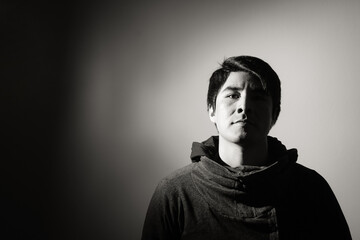Retrato de hombre joven latino serio, molesto. Iluminación artística lateral y sombras marcadas,...