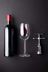 Rolgordijnen Bottle of red wine, glass and corkscrew on black background, with copy space © vectorfusionart