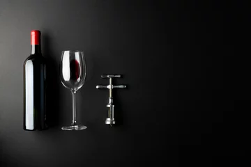Sierkussen Bottle of red wine, glass and corkscrew on black background, with copy space © vectorfusionart