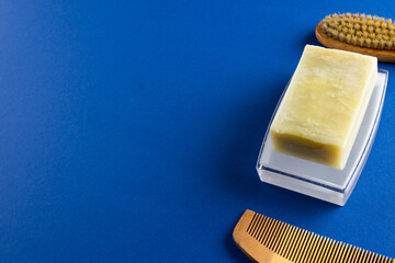 Image of hair brush, comb and soap with copy space on blue background