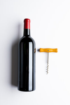Bottle of red wine and corkscrew on white background, with copy space