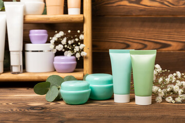 Wooden shelf with cosmetics on a brown wall background.Cosmetic products set. Shelf in the bathroom with a set of cosmetic bottles, skin care cosmetics, body cream, shampoo, bath accessories.Body care