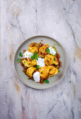 Traditional oriental manti dumplings with spicy minced meat and yogurt served as top view in a Nordic design plate with text free space