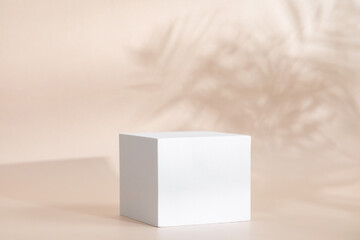 Beige pastel background for product presentation with shadow, tropical palm leaves and light. Podium, stage pedestal platform for cosmetic product. Empty square podium. Mockup.