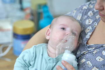 A sick child breathes with a nebulizer mask with a steam inhaler due to a respiratory disease. A...