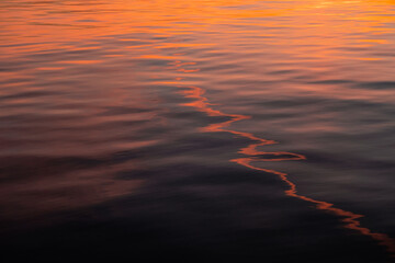Sunset reflections on water, orange background, calming texture of water