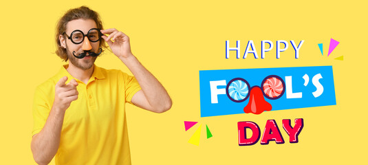 Funny young man in disguise on yellow background. April Fools' Day