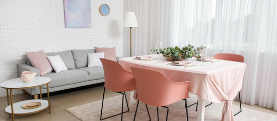 Interior of stylish dining room with beautiful table setting and grey sofa