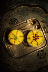 two servings of Sholeh Zard, a Persian saffron rice pudding, dessert with cinnamon, pomegranate and pistachio garnish