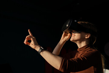 Using virtual reality glasses, a young woman passionate about the game pressing a virtual button.