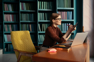 A modern office assistant using the Internet online working on a startup project.  A woman with glasses, the concept of an employee.