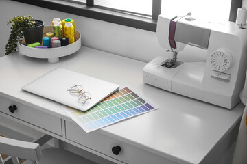 Tailor's workplace with laptop and sewing machine in atelier