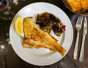 Delicious roasted sole fish served with stewed vegetables and fresh lemon. Healthy seafood dinner