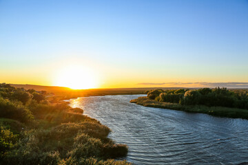 View of beautiful river with green bushes at sunset
