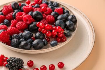 Plate with fresh berries on color background, closeup