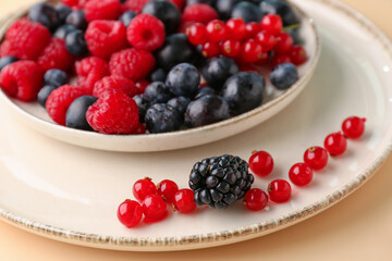 Plate with fresh berries on color background, closeup