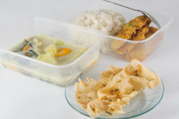 sayur Lodeh, Indonesian food, with white rice and side dishes of fried tempeh and rempeyek teri or anchovies, isolated on a white background