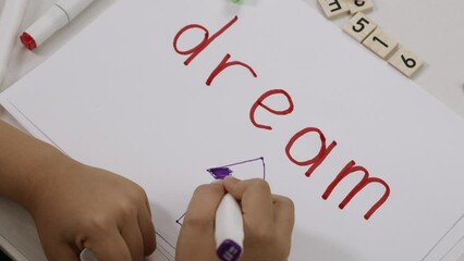 Word DREAM written by a child on a paper.