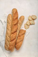 Loaves of fresh baguette and napkin on white background