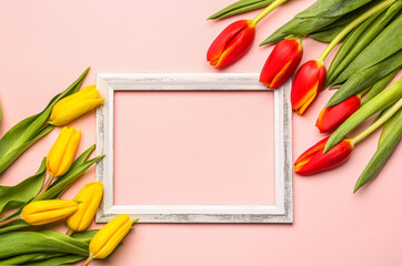 Composition with empty picture frame and beautiful tulip flowers on pink background. Hello spring