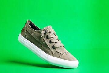 Walking canvas shoes - sneakers. Modern fashionable shoes on a green background close-up.