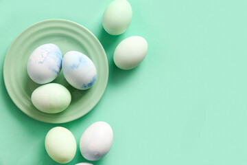 Plate of beautiful Easter eggs on color background