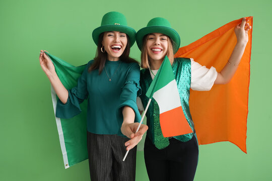 Young women with flags of Ireland on green background. St. Patrick's Day celebration