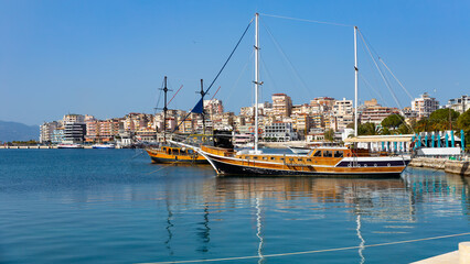 Fototapeta na wymiar View of vintage wooden sailboats moored in harbor of coastal tourist city of Sarande on Ionian Sea in Albania on sunny spring day.