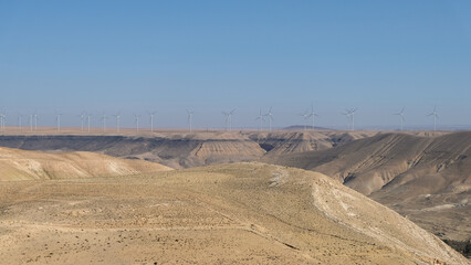 Vast, remote Arabian desert panoramic landscape view with wind turbine farm in Jordan, Middle East