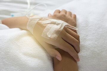 Photo of a hand with an IV in a hospital.Asian woman lying sick in hospital