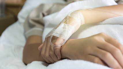 Photo of a hand with an IV in a hospital.Asian woman lying sick in hospital