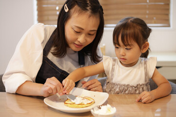 Obraz na płótnie Canvas ホットケーキにクリームを塗る親子