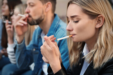 People smoking cigarettes at public place outdoors, closeup