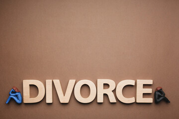 Word Divorce made of wooden letters and plasticine people figures on brown background, flat lay....
