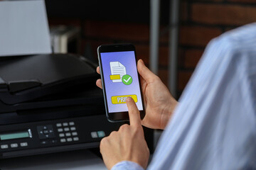 Man using printer management application on mobile phone indoors, closeup. Image on device screen.