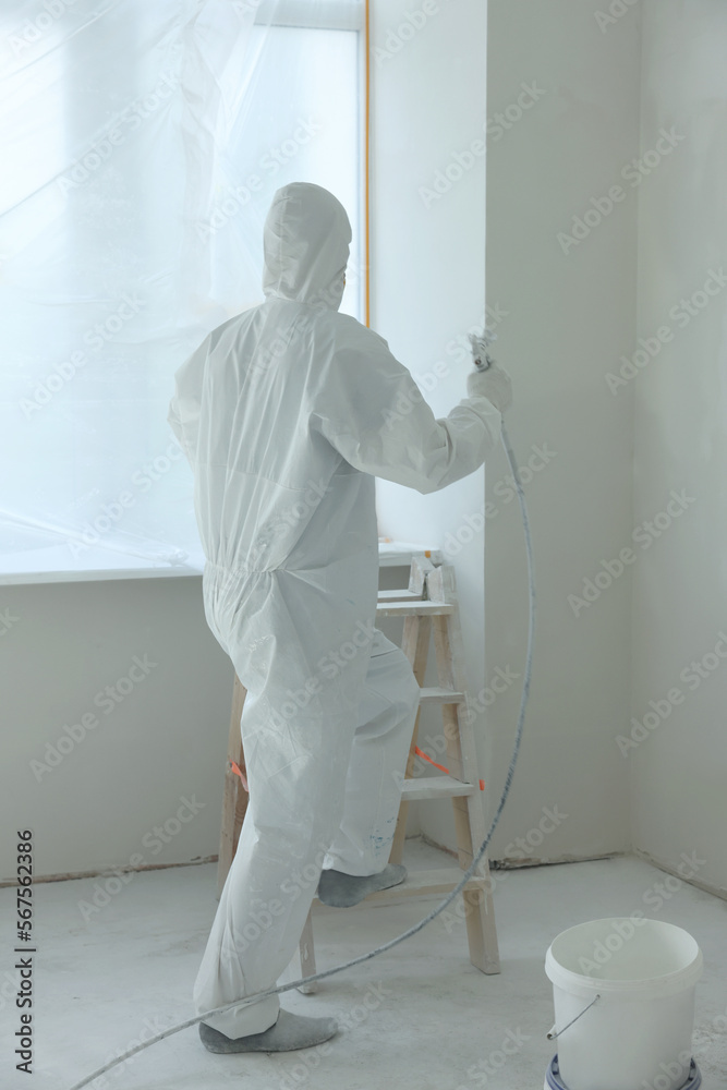 Canvas Prints Decorator painting window slope on ladder indoors, back view