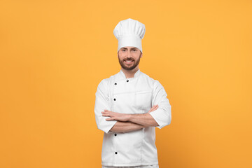 Smiling mature male chef on orange background