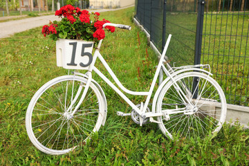 Fototapeta na wymiar White bicycle with number 15 on basket of flowers outdoors