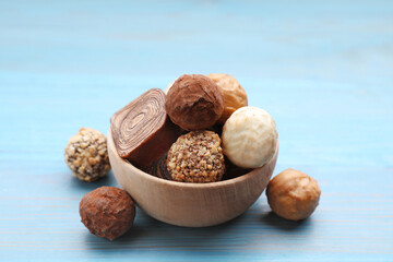 Tasty chocolate candies on light blue wooden table